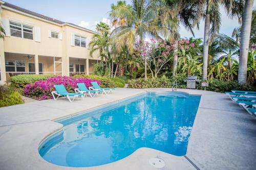 Una piscina con sillas azules y un edificio. en GRACEBAY TOWNHOMES B3, 5 minutes walk to gracebay beach, en Long Bay Hills