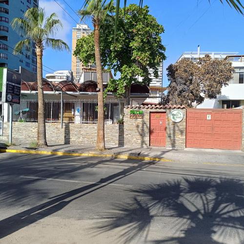 an empty street with palm trees and a fence at Palm Hostal in Iquique