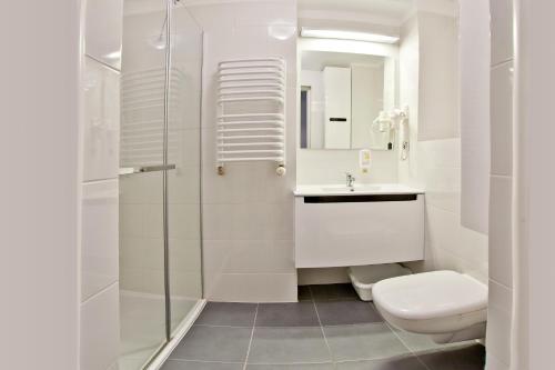 a white bathroom with a toilet and a sink at Urocza Art Pensjonat in Krynica Zdrój
