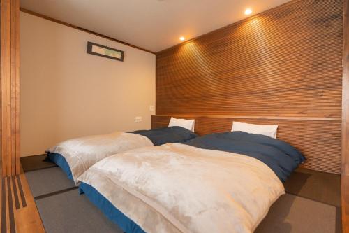 two beds in a bedroom with a large window at Nozawa Onsen Azegamikan in Nozawa Onsen