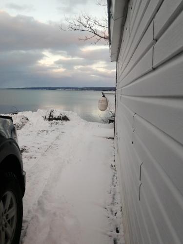 a snow covered side of a house with a body of water at 78 Montague in Digby