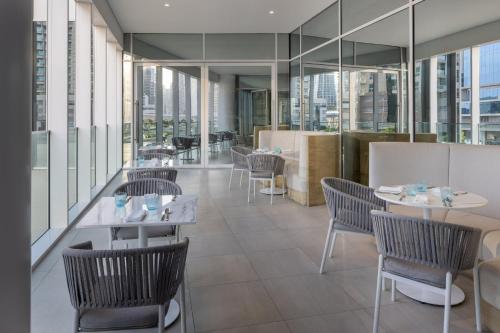 a restaurant with tables and chairs and windows at Holiday Inn Dubai Business Bay by IHG in Dubai