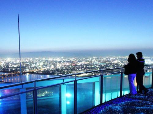 two people standing on the edge of a city skyline at EZ HOTEL Kansai Airport Seaside in Izumi-Sano