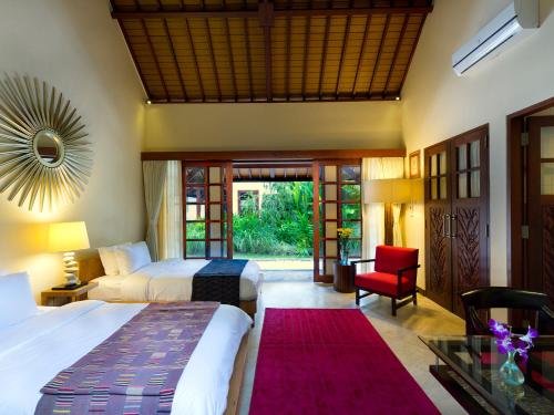 una habitación de hotel con 2 camas y una silla roja en Villa San, en Ubud