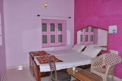een slaapkamer met een bed en een roze muur bij Thilak Home Stay in Hampi
