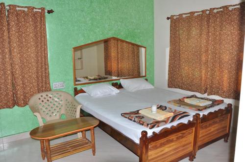 a bedroom with a bed with a mirror and a chair at Thilak Home Stay in Hampi