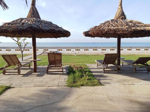a group of chairs and umbrellas on the beach at Biển Ngọc Homstay in Ấp Sung Xuân