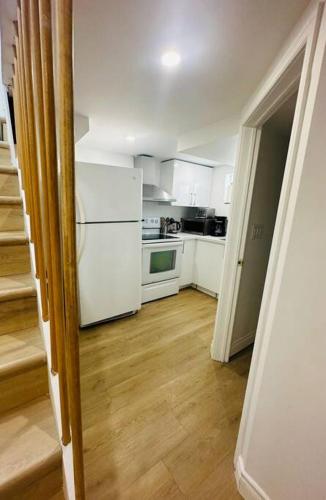 a kitchen with white appliances and a wooden floor at Newly renovated, laundry, separate entrance in Richmond Hill