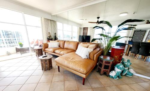 a living room with a leather couch and a plant at 19th Avenue on the Beach in Gold Coast