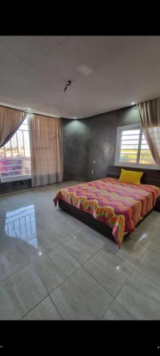 a bedroom with a large bed in a room with windows at Belle maison de campagne in Kenitra
