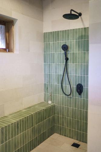 a green tiled shower with a shower head in a bathroom at Makai Medewi in Airsatang