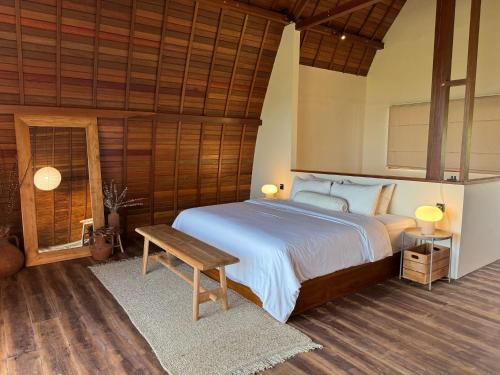 a bedroom with a large bed and a wooden ceiling at Makai Medewi in Airsatang