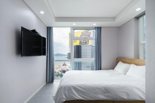 a bedroom with a bed and a large window at Elysia Boutique Hotel in Busan
