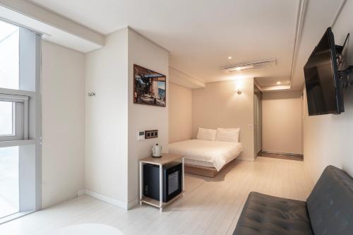 um quarto com uma cama e uma televisão num quarto em Elysia Boutique Hotel em Busan