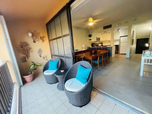 a room with chairs and a table and a kitchen at Condo in Palmas Del Mar - 5 min walk to Palmanova Plaza in Playa de Guayanes