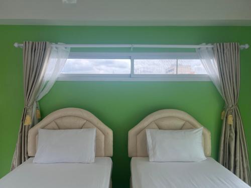 two beds in a green room with a window at Bonita House in Bangkok