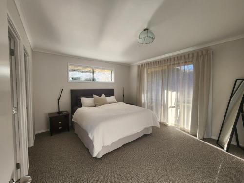 a bedroom with a white bed and a window at Karapiro Apartment in Cambridge