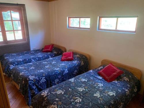 two beds in a room with red pillows on them at Cabaña familiar huaqui in El Arrayán