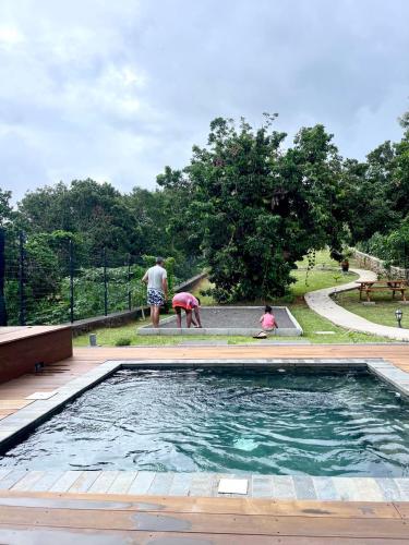 a group of people standing around a swimming pool at Austral House-chalet sud sauvage in Saint-Joseph