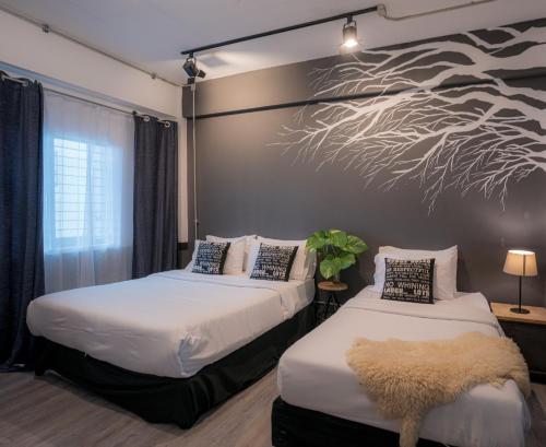 twee bedden in een kamer met een muurschildering van bomen aan de muur bij 2 Bedrooms 1 living room near Old City in Chiang Mai