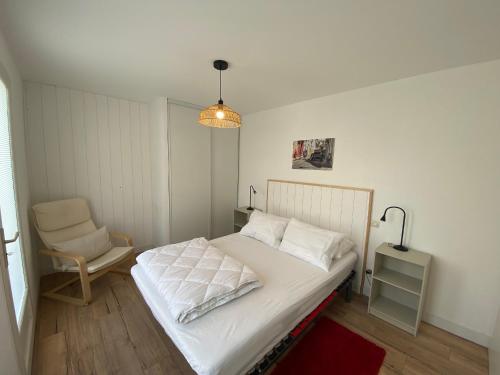 una camera da letto con un letto bianco e una sedia di Charmante Maison près de la Plage et du Centre-Ville, Terrasse, TV, Cuisine Equipée à Fouras - FR-1-709-76 a Fouras