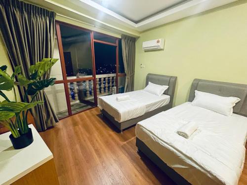 a room with two beds and a balcony with a plant at Kuching City Center Riverbank Suites With Marvelous River View in Kuching