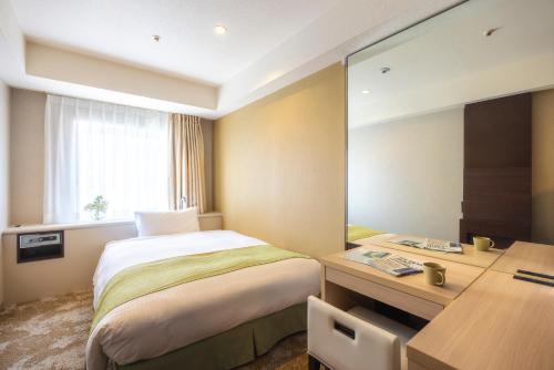 1 dormitorio con cama, escritorio y espejo en Shinjuku Washington Hotel Annex, en Tokio