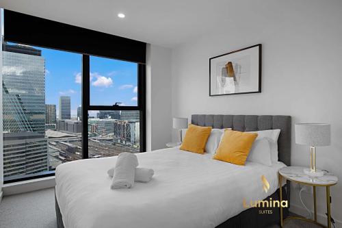 a bedroom with a large bed with a large window at Lumina Suites in Melbourne