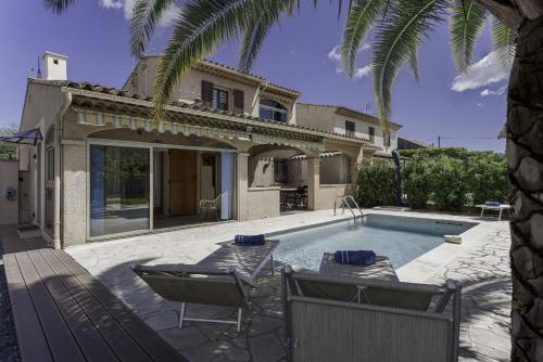 une piscine avec des chaises et une maison dans l'établissement Casa Mia by Halldis, à Mandelieu-la-Napoule