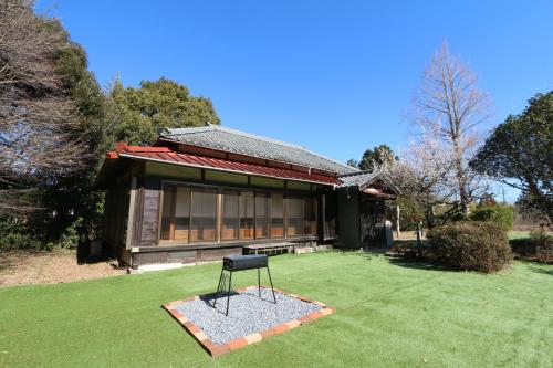 a black chair in the grass in front of a house at 白子ハウス in Goi
