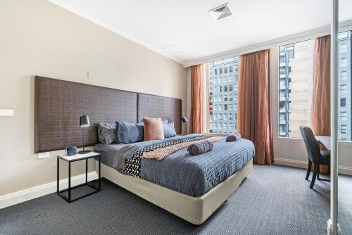 een slaapkamer met een groot bed en een groot raam bij Style and Convenience on Little Bourke in Melbourne