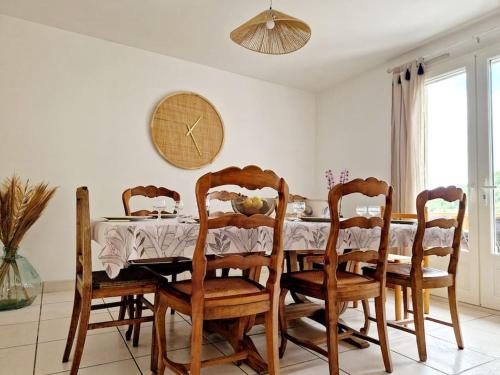 une salle à manger avec une table, des chaises et une horloge dans l'établissement Maison Le Yoti, jolie vue sur le Lot, à Campouriez