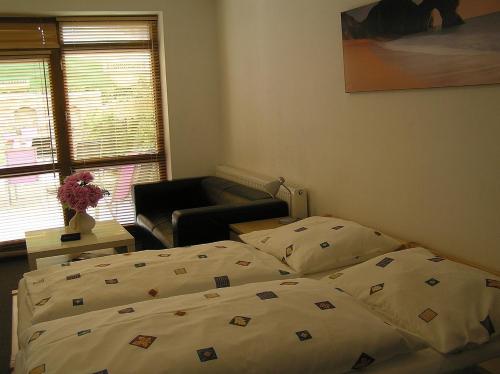 a bedroom with a bed and a chair and a window at Penzion Marriot in Trnava