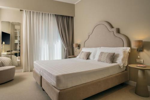 ein Schlafzimmer mit einem großen weißen Bett mit einem großen Fenster in der Unterkunft Hotel Capri in Sorrent