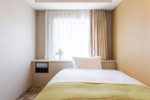 1 dormitorio con cama blanca y ventana en Shinjuku Washington Hotel Annex en Tokio