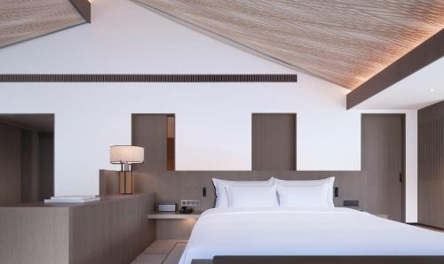a bedroom with a large white bed and wooden ceilings at Yangshuo Sugar House in Yangshuo