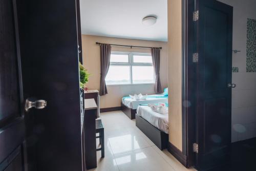 a small room with two beds and a window at V Hotel Vientiane in Vientiane