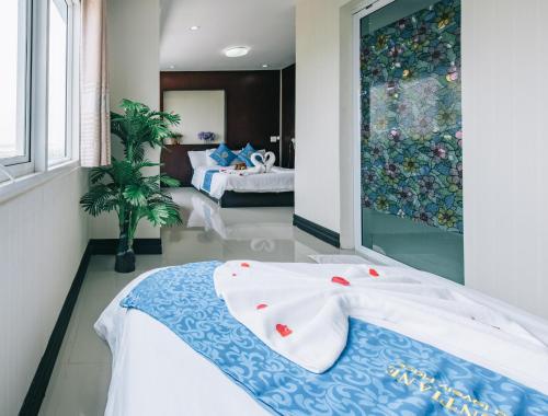 a bedroom with two beds and a large window at V Hotel Vientiane in Vientiane