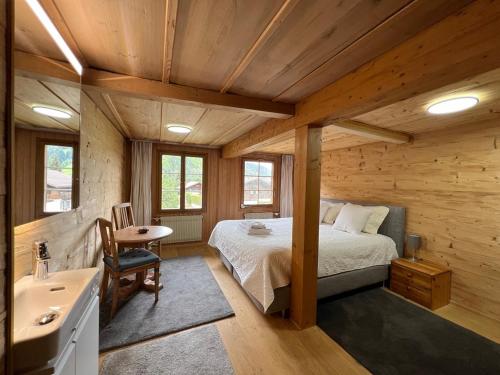 1 dormitorio en una cabaña de madera con 1 cama y lavamanos en Haus Bergmann en Boltigen