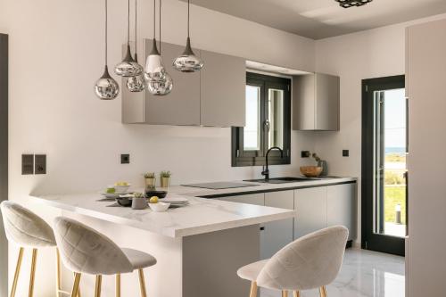 a white kitchen with white cabinets and white chairs at The Ionian Sea & Sunset View Villa in Minia