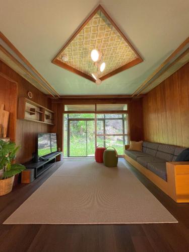 a living room with a couch and a large window at 大人数の家族旅行に！BBQ/シアタールーム/カラオケ/日本庭園 in Furano