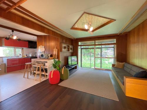 a living room with a couch and a table and a kitchen at 大人数の家族旅行に！BBQ/シアタールーム/カラオケ/日本庭園 in Furano