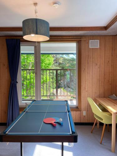 a ping pong table in a room with a window at 大人数の家族旅行に！BBQ/シアタールーム/カラオケ/日本庭園 in Furano