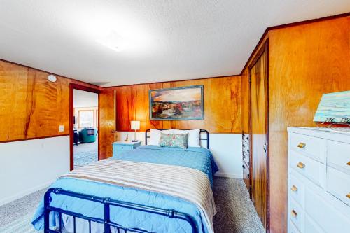 a bedroom with a bed and a wooden wall at Coastal Vista Retreat in Coos Bay