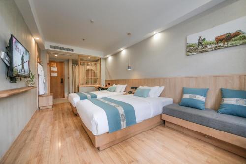 a hotel room with two beds and a couch at Meadow Lodge Hotel Taizhou in Taizhou