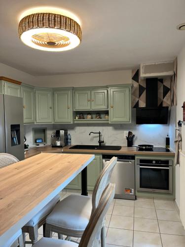 une cuisine avec des placards verts et une table en bois dans l'établissement À 5 minutes à pieds du château, 2 belles et spacieuses chambres, SDB, WC et un garage privé à 25 minutes circuit 24h, à Le Grand-Lucé