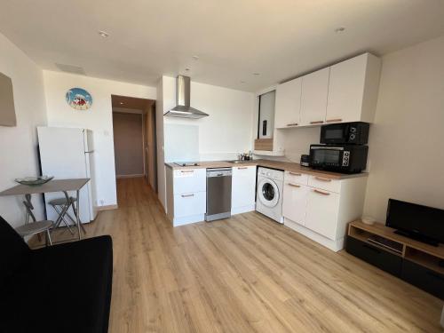 una cucina con mobili bianchi, lavatrice e asciugatrice di Appartement t2 vue mer a Saint-Cyprien