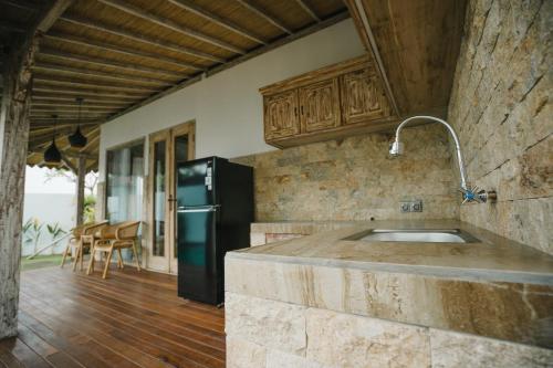 cocina con fregadero y nevera negra en Lungid Sari Uluwatu, en Uluwatu