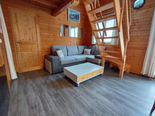 a living room with a couch and stairs in a cabin at Chalet individuel à proximité de la station Les 7 Laux in Les Adrets