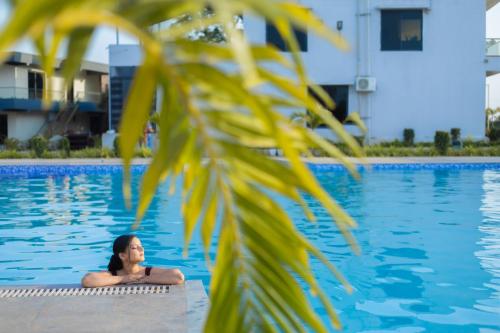 a woman laying in a swimming pool at Daksh Eden Greenz -A Luxury Resort in Sasan Gir in Sasan Gir